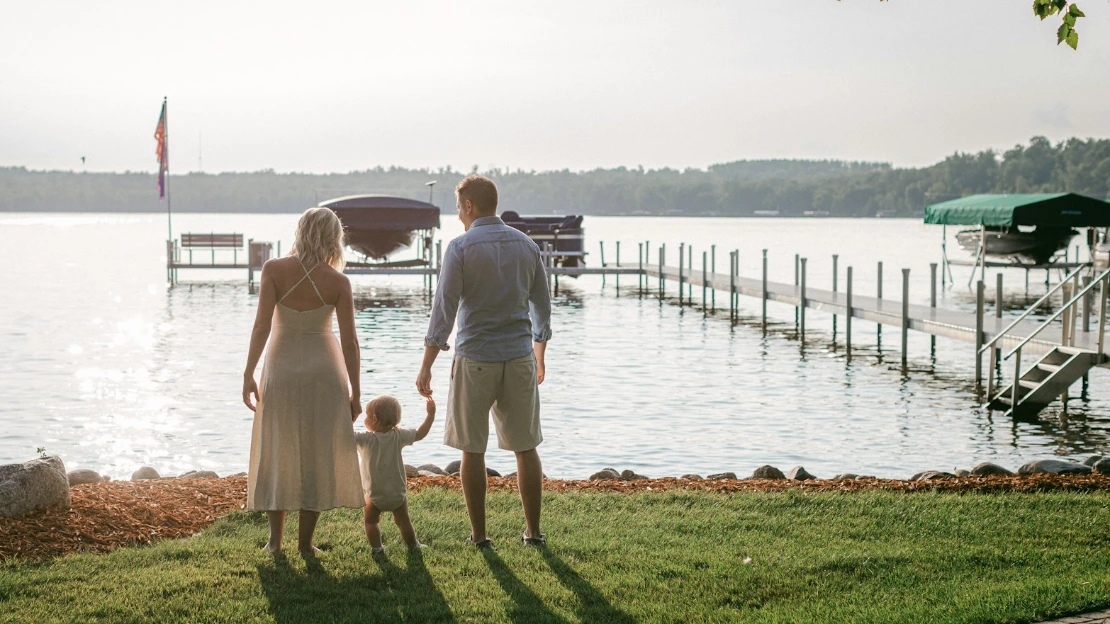 a man and a woman are standing on the grass by the water